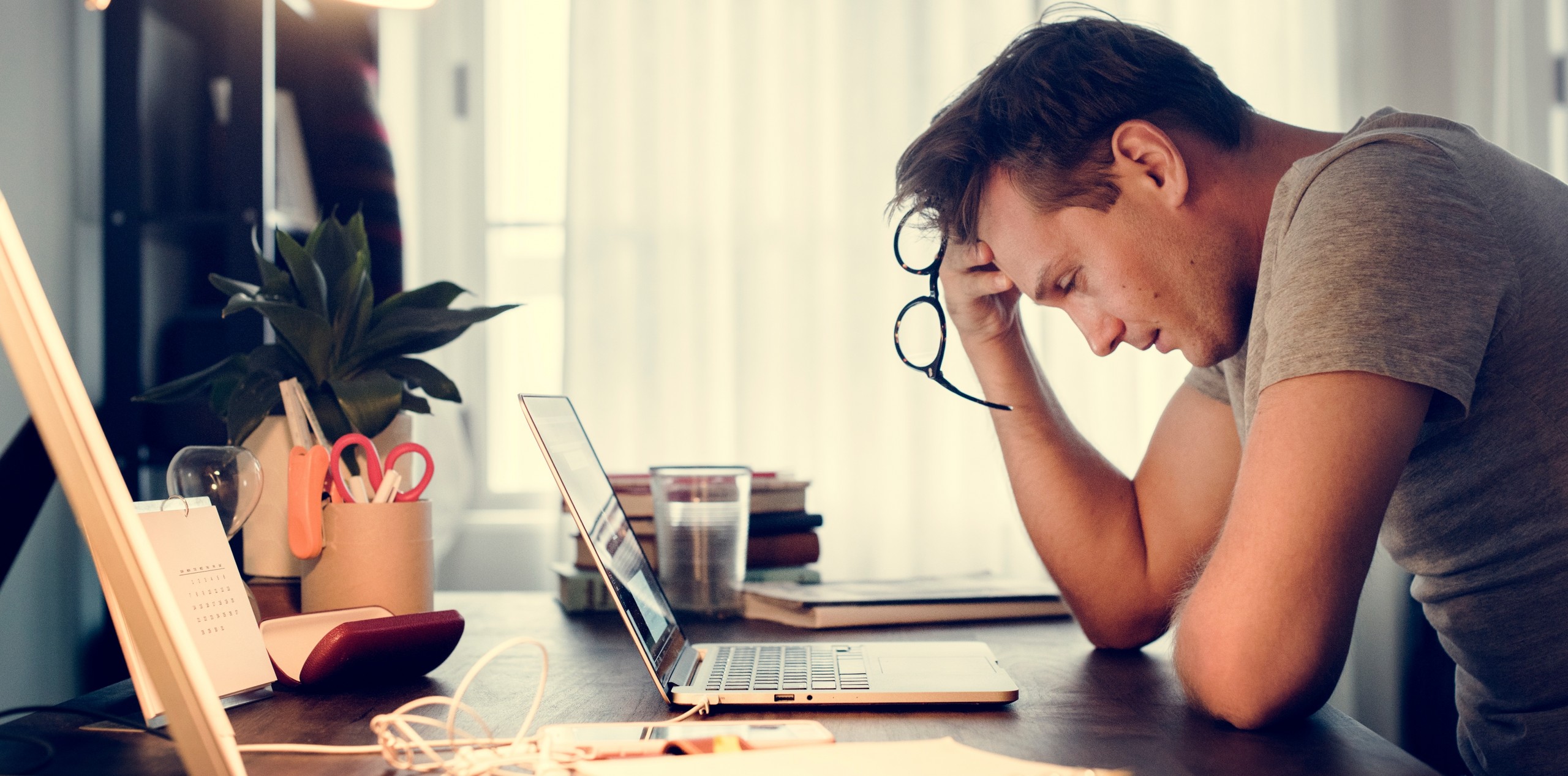 Man working on laptop at desk looking upset