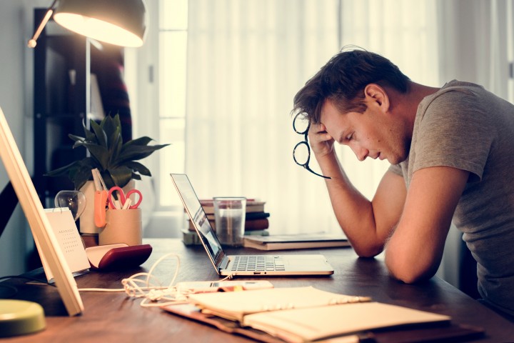 Man working on laptop at desk looking upset